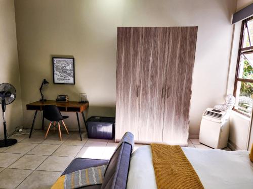 a bedroom with a bed and a desk and a table at No Loadshedding Fast WiFi Lux Apartment in Johannesburg