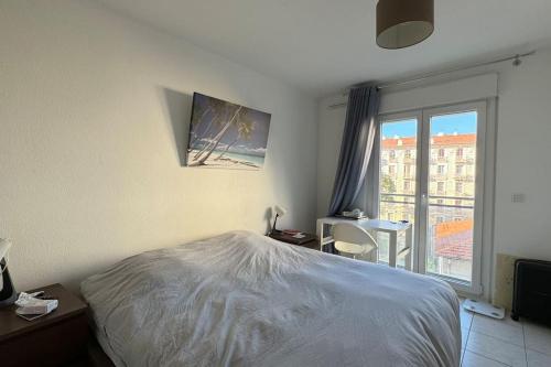 une chambre avec un lit et une grande fenêtre dans l'établissement Nice Proche Mer, à Nice
