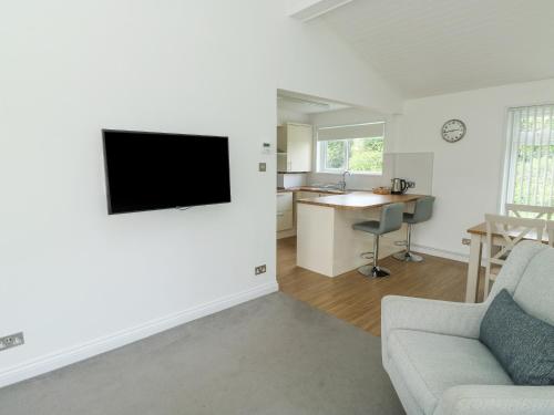 a living room with a couch and a tv on a wall at Harcombe House Bungalow 1 in Newton Abbot