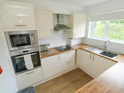 a kitchen with white cabinets and a sink at Harcombe House Bungalow 1 in Newton Abbot
