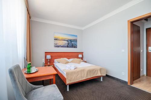 a bedroom with a bed and a table and a chair at Hotel Wodnik Twój Hotel z widokiem na morze in Ustronie Morskie