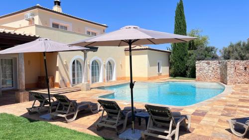 una piscina con sedie e ombrelloni accanto a una casa di Vila Relaxmountain B&B a São Bartolomeu de Messines