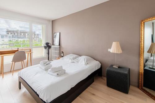 une chambre avec un lit avec des draps blancs et un miroir dans l'établissement Meuniers - Spacieux appartement proche Bois de Vincennes, à Paris