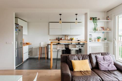 un salon avec un canapé et une cuisine dans l'établissement Meuniers - Spacieux appartement proche Bois de Vincennes, à Paris