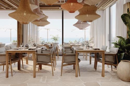 - un restaurant avec des tables, des chaises et de grandes fenêtres dans l'établissement LIOQA Resort, à Ugljan