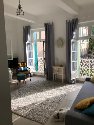 un salon avec un canapé et deux grandes fenêtres dans l'établissement Best View Appartement Béziers, à Béziers