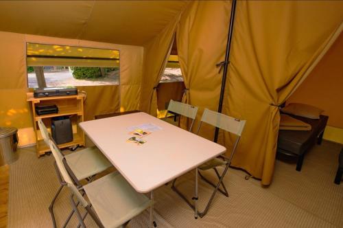 une tente avec une table et des chaises dans une chambre dans l'établissement Camping Onlycamp Les Berges de l'Yonne, à Coulanges-sur-Yonne