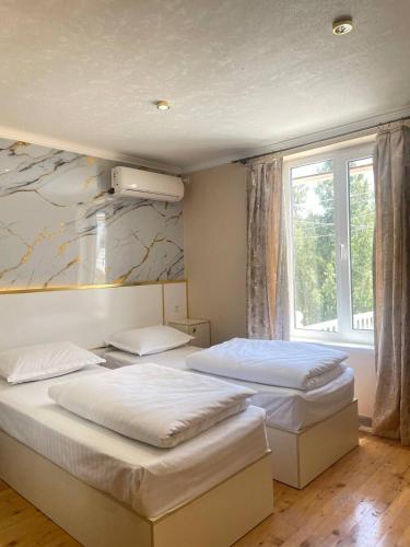two beds in a room with a window at Horizon Boutique in Samarkand