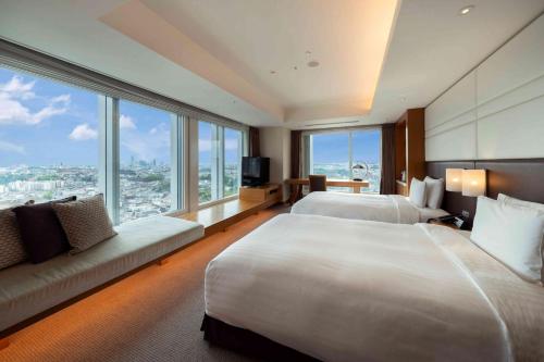 a hotel room with two beds and a large window at Hotel Associa Shin-Yokohama in Yokohama