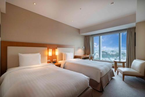 a hotel room with two beds and a window at Hotel Associa Shin-Yokohama in Yokohama
