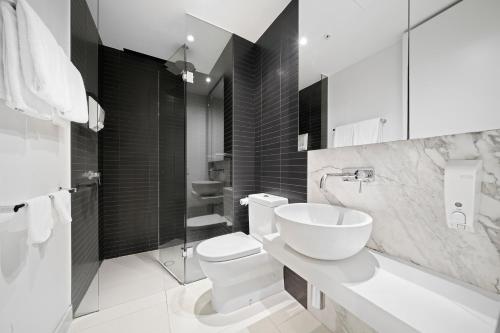 a white bathroom with a toilet and a sink at Flinders Street Apartments in Melbourne