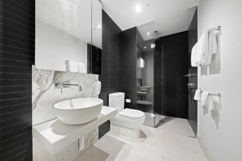 a black and white bathroom with a sink and a toilet at Flinders Street Apartments in Melbourne
