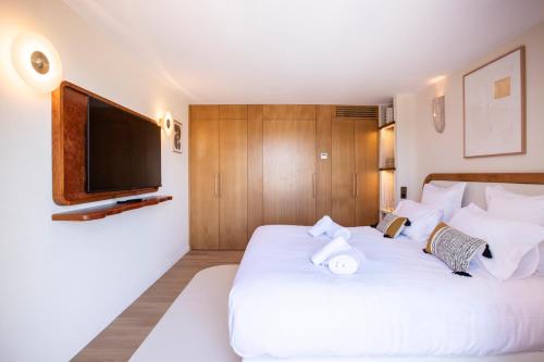a bedroom with a white bed and a flat screen tv at Tinah Saint-Tropez in Saint-Tropez