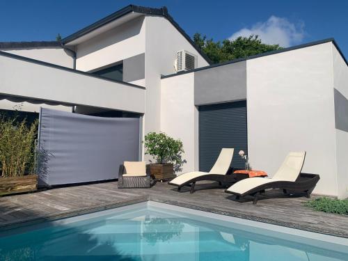 un patio avec deux chaises et une piscine dans l'établissement le moulin blanc, à Castelmaurou