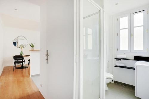 La salle de bains blanche est pourvue de toilettes et d'un miroir. dans l'établissement Lumineux 2 pièces Batignolles, à Paris