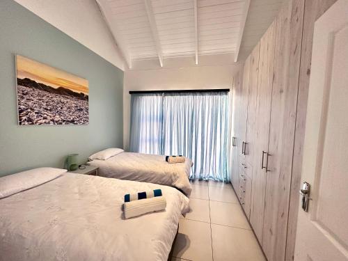 a bedroom with two beds and a window at The Dunes in Yzerfontein