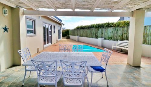 a patio with a table and chairs and a pool at The Dunes in Yzerfontein