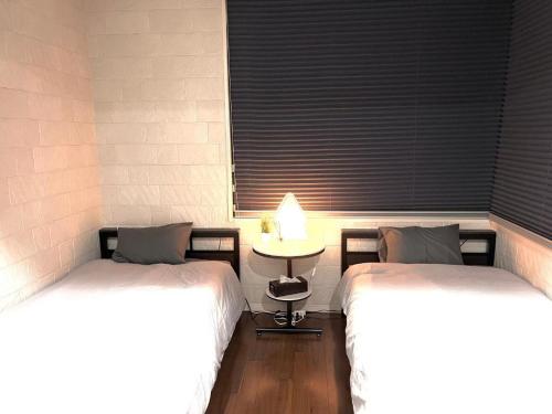 a room with two beds and a table with a window at Shibuya Harajuku Big House in Tokyo