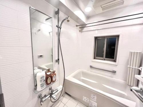 a white bathroom with a tub and a sink at Shibuya Harajuku Big House in Tokyo
