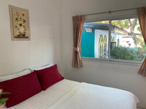 una camera da letto con un letto con cuscini rossi e una finestra di D Heart Homestay a Bangkok