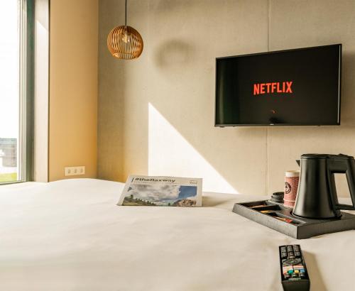 a bed with a tv and a book and a remote control at das flax allgäu in Dietmannsried