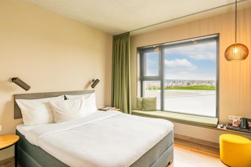 a hotel room with a bed and a large window at das flax allgäu in Dietmannsried