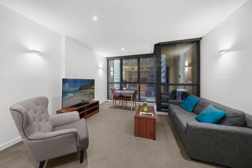 a living room with two couches and a tv at Flinders Street Apartments in Melbourne
