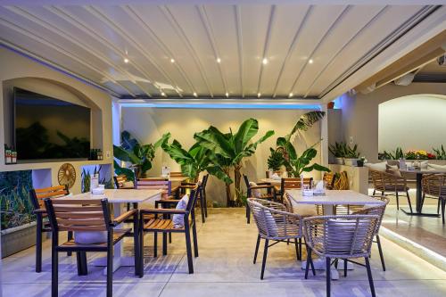 a restaurant with tables and chairs and plants at Mila Malia Studios Hotel in Malia