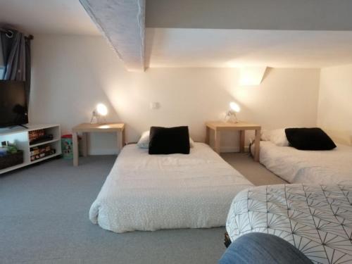 a bedroom with two beds and two tables and a tv at L'Entre Vagues in Saint-Jean-de-Monts