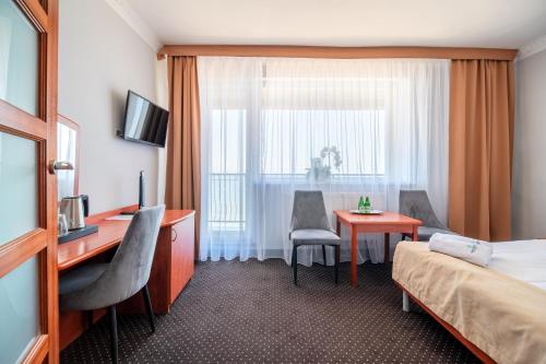 a hotel room with a bed and a desk and a table at Hotel Wodnik Twój Hotel z widokiem na morze in Ustronie Morskie