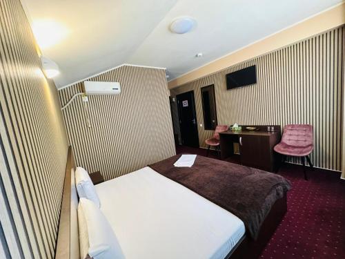 a hotel room with a bed and a desk at Hotel Athos in Bucharest