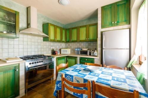 a kitchen with green cabinets and a table and a refrigerator at Villetta Macchia Mediterranea in Cuglieri