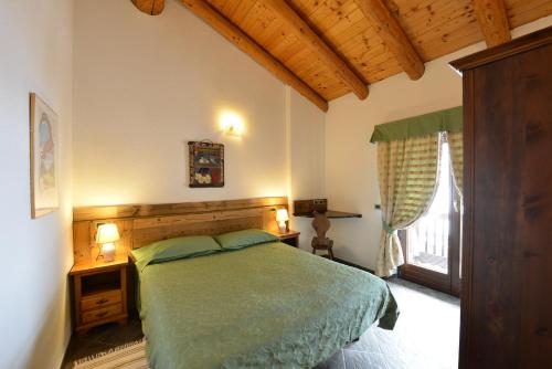 een slaapkamer met een groen bed en een raam bij Residence Au Vieux Grenier in Cogne