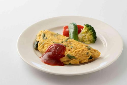 a white plate with a omelet and vegetables on it at Hotel Associa Shin-Yokohama in Yokohama
