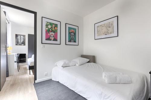 - une chambre avec un lit blanc et des photos sur le mur dans l'établissement Charming Apartment 1BR in heart of 10th, à Paris