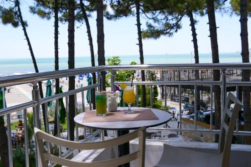 a table with two drinks on a balcony with the beach at Hotel Andi in Durrës