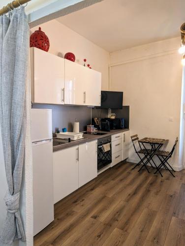 une cuisine avec des armoires blanches et un plancher en bois dans l'établissement Appartement cosy proche du port, à Nice