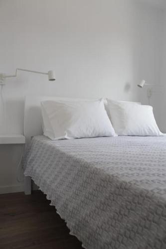 a bed with white sheets and pillows and a table at Casa na Aldeia in Arcos de Valdevez