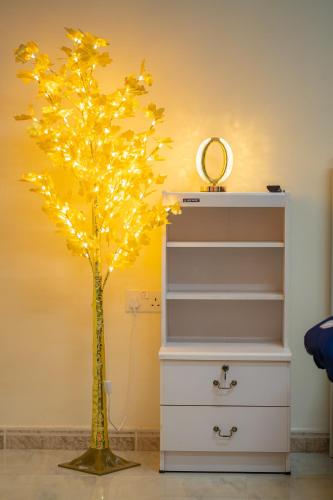a christmas tree with lights in a dresser at BAITH AL JANNAH Family room in Abu Dhabi