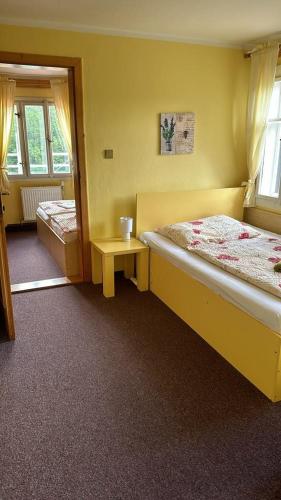 a yellow room with two beds and a table at Chata Orlice in Bartošovice v Orlických Horách