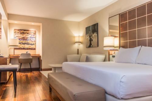 ein Hotelzimmer mit einem großen Bett und einem Schreibtisch in der Unterkunft Eurostars Diana Palace in Palencia