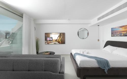 a white bedroom with a bed and a couch at סוויטות עם נוף וצמודות לים במתחם SeaSide היוקרתי עם בריכה - By SEAELO EILAT in Eilat