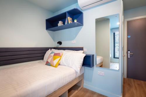 Schlafzimmer mit einem Bett mit blauen Wänden und einem Spiegel in der Unterkunft Coleman Court Summer Apartments in Cork
