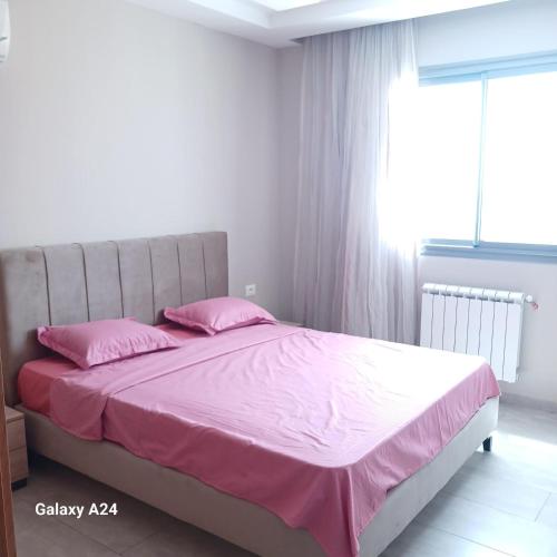 a bedroom with a bed with pink sheets and a window at Appartement Panorama in Kelibia