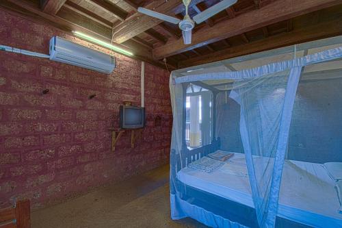 a bedroom with a canopy bed and a tv at Konkan Nest Resort in Ganpatipule