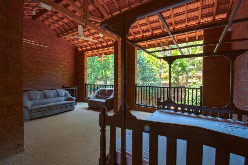 a living room with a large window and a couch at Konkan Nest Resort in Ganpatipule