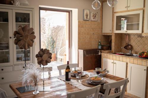 cocina con mesa y botella de vino en Baita Naturas con piscina idromassaggio calda, privata e gratuita, en Rossana