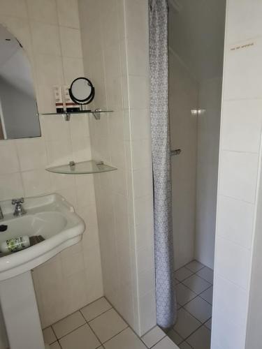 a white bathroom with a sink and a shower at Romantisch Gastenverblijf t'Klomperhuys in Lunteren