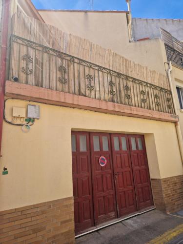 - un bâtiment avec deux portes rouges et un balcon dans l'établissement Appartement avec terrasse Saint Laurent de la salanque, à Saint-Laurent-de-la-Salanque