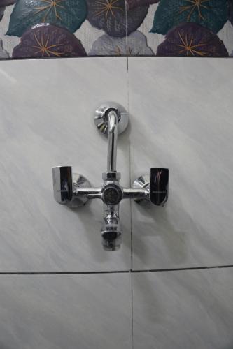 a faucet on a white tiled wall at Luxury Room with 1 Double Bed in Haridwār